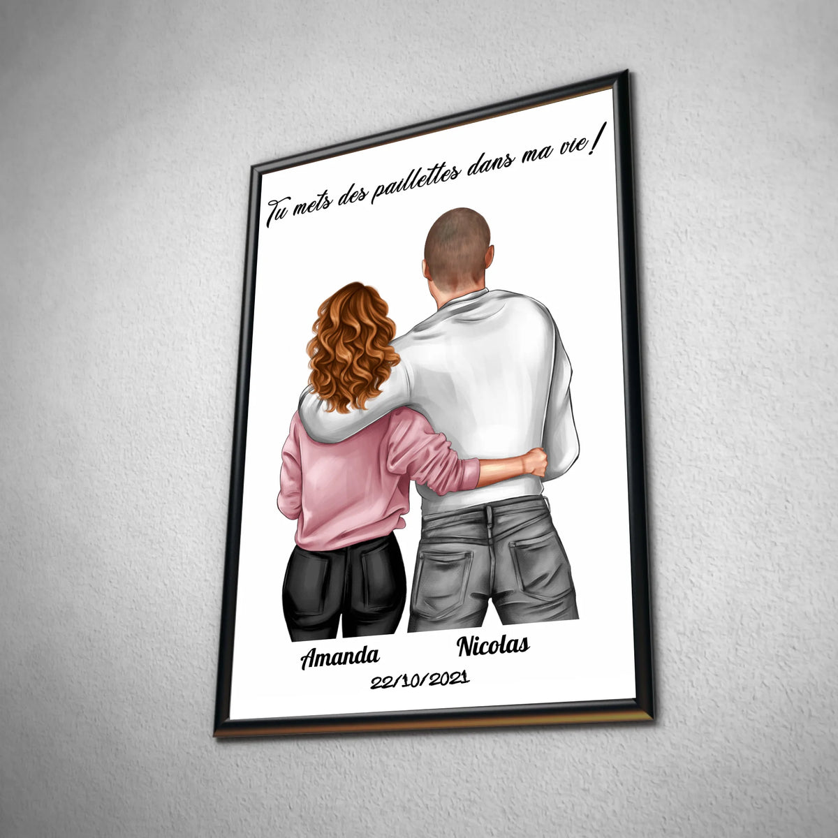 Tableau couple personnalisé homme et femme en affiche encadrée noire, vue inclinée sur un mur gris