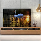 Tableau Décoratif Cygne en verre acrylique, posé sur un meuble TV en bois devant un mur en béton
