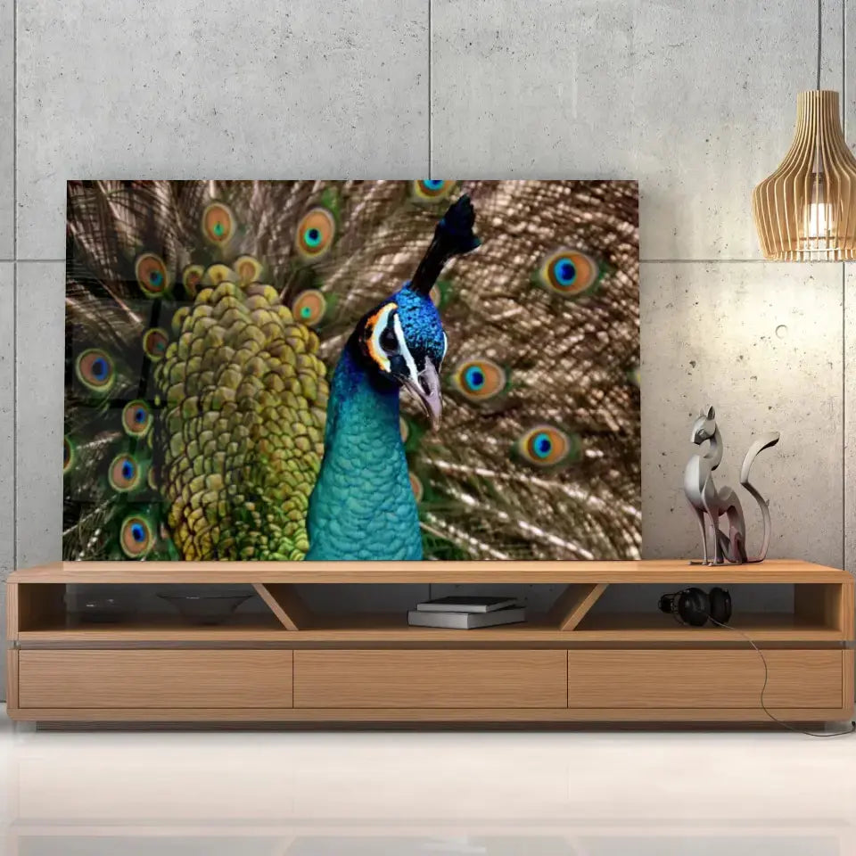 Tableau Décoratif Paon Vue de Face en verre acrylique, posé sur un meuble TV en bois devant un mur en béton