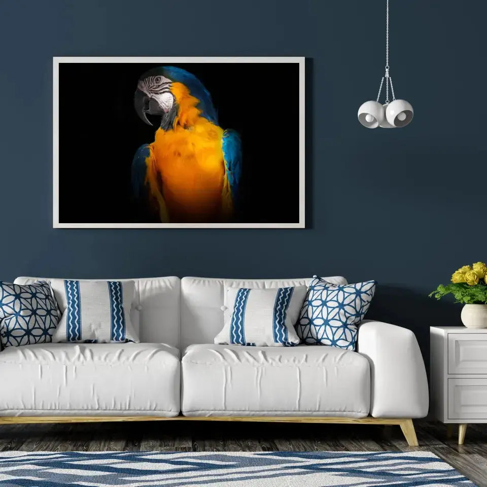 Tableau Décoratif Perroquet Tropical en affiche encadrée dans un salon bleu nuit au-dessus d'un canapé blanc