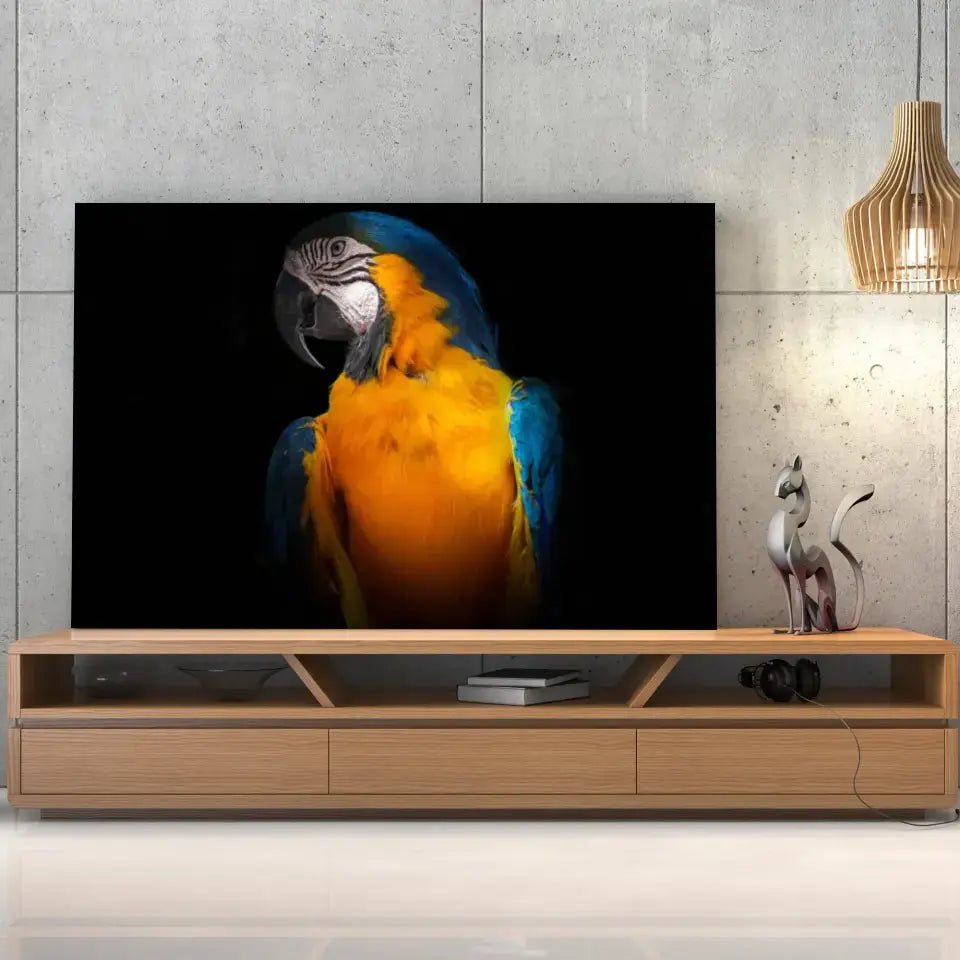 Tableau Décoratif Perroquet Tropical sur toile, posée sur un meuble TV en bois devant un mur en béton