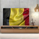 Tableau Drapeau Belgique sur toile, posée sur un meuble TV en bois devant un mur en béton