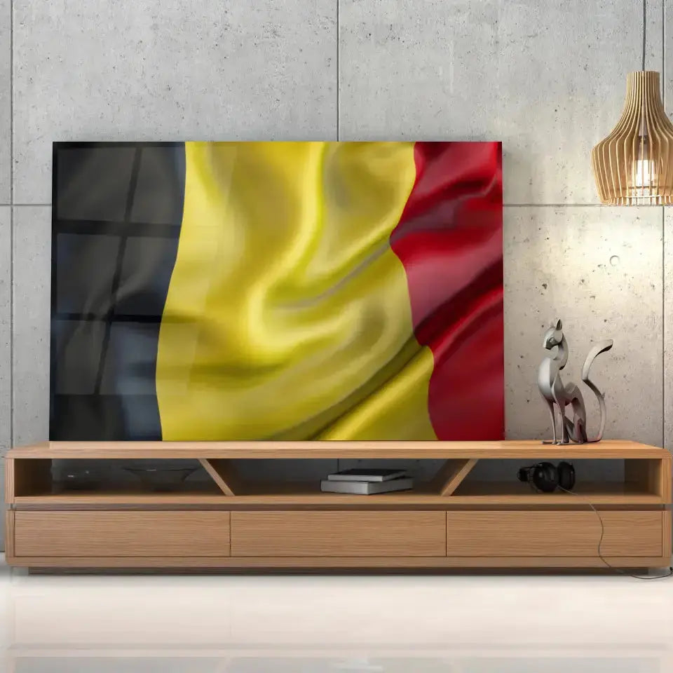 Tableau Drapeau Belgique en verre acrylique, posé sur un meuble TV en bois devant un mur en béton