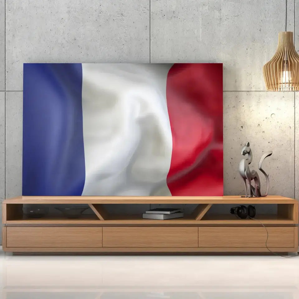 Tableau Drapeau France sur toile, posée sur un meuble TV en bois devant un mur en béton