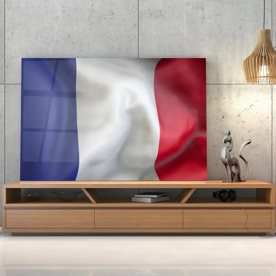 Tableau Drapeau France en verre acrylique, posé sur un meuble TV en bois devant un mur en béton