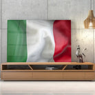 Tableau Drapeau Italie en verre acrylique, posé sur un meuble TV en bois devant un mur en béton