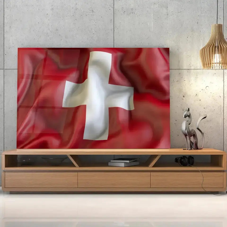 Tableau Drapeau Suisse en verre acrylique, posé sur un meuble TV en bois devant un mur en béton