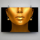 Tableau Femme maquillage en or en affiche suspendue par des pinces sur un mur gris
