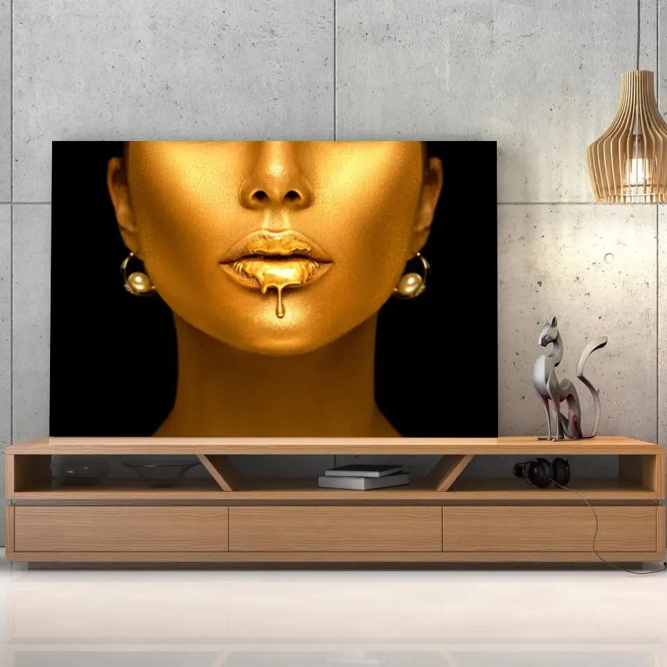 Tableau Femme maquillage en or sur toile, posée sur un meuble TV en bois devant un mur en béton