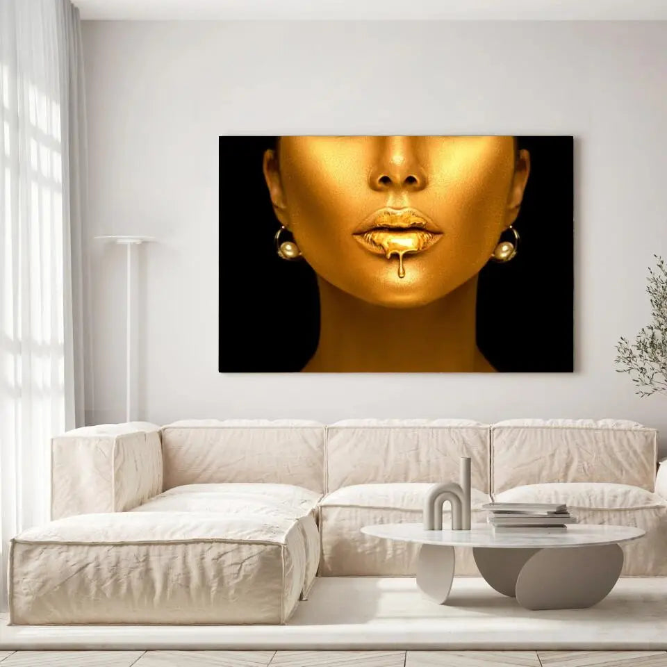 Tableau Femme maquillage en or sur toile, accrochée dans un salon lumineux au-dessus d'un canapé beige