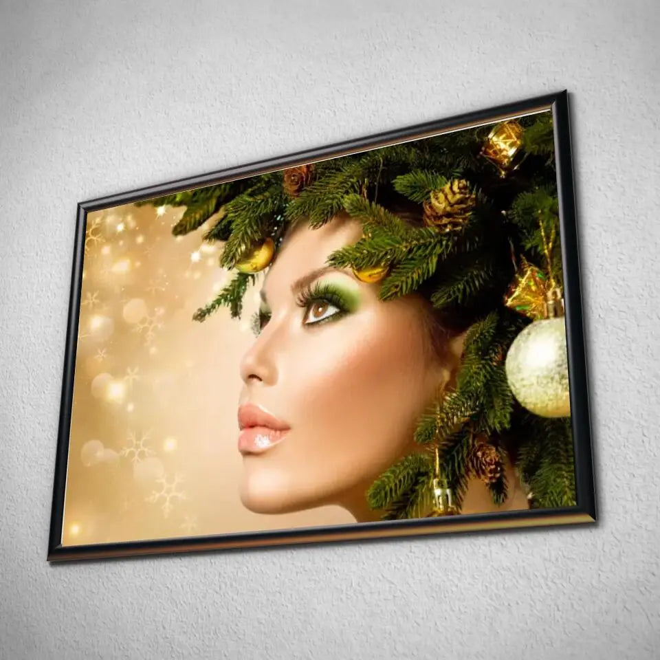 Tableau Femme noël en or en affiche dans un cadre noir, vue inclinée sur un mur gris
