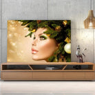 Tableau Femme noël en or sur toile, posée sur un meuble TV en bois devant un mur en béton