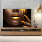 Tableau Lèvre et or liquide sur toile, posée sur un meuble TV en bois devant un mur en béton