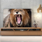 Tableau Décoratif Lion Rugissant en verre acrylique, posé sur un meuble TV en bois devant un mur en béton