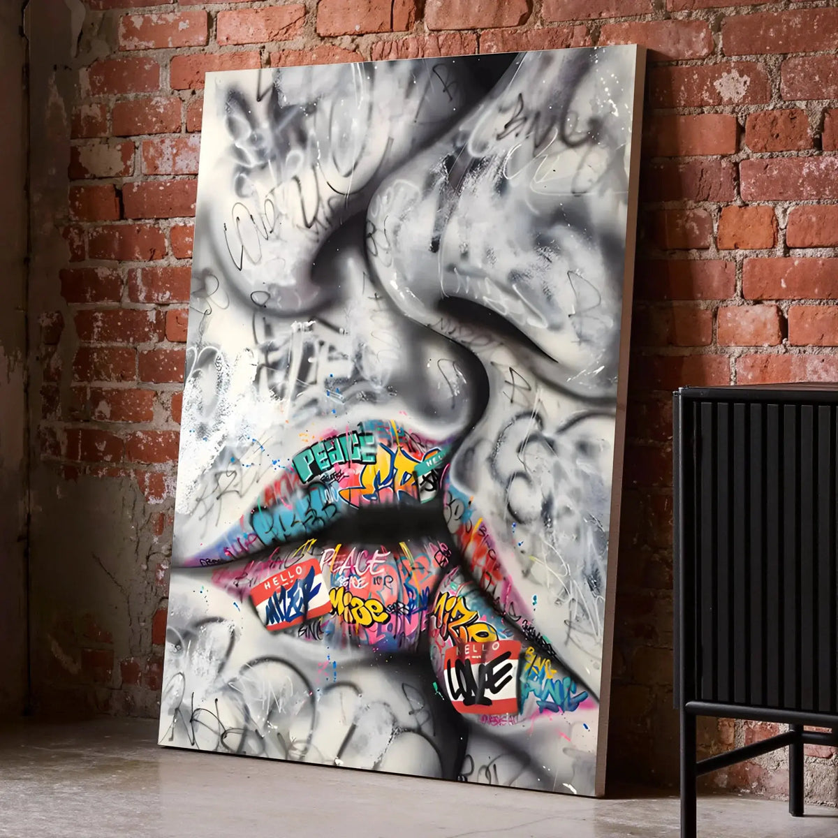 Tableau Street Art Baiser Urbain sur toile, posé au sol contre un mur de briques rouges