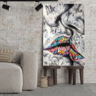 Tableau Street Art Baiser Urbain sur toile, posé sur des tabourets devant un mur de briques