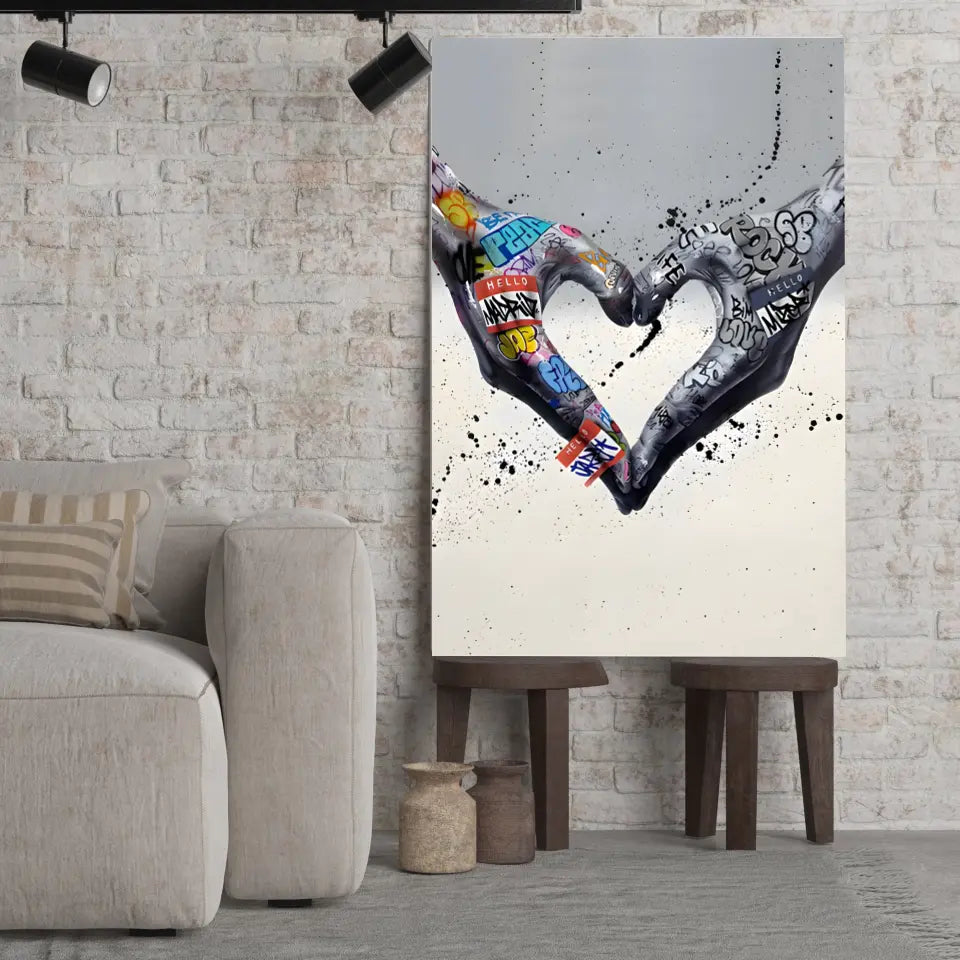 Tableau Street Art Cœur Créatif sur toile, posé sur des tabourets devant un mur de briques