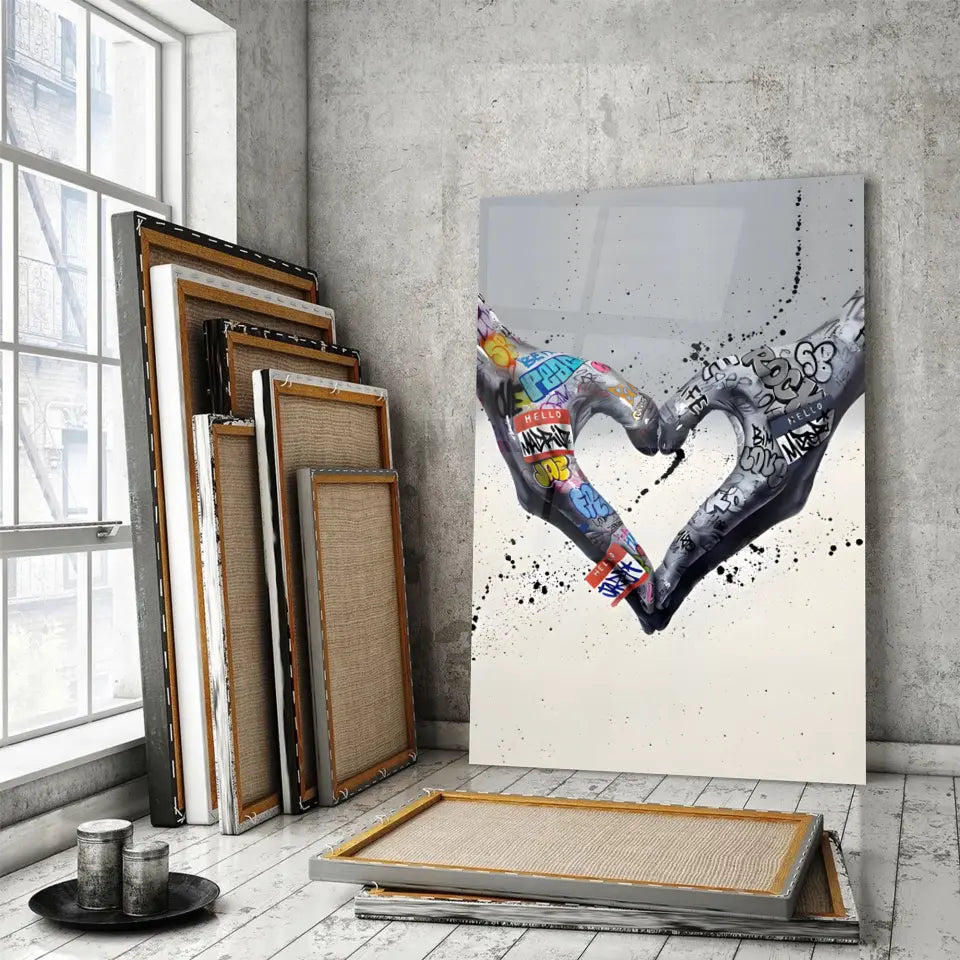 Tableau Street Art Cœur Créatif en verre acrylique, posé devant des cadres empilés