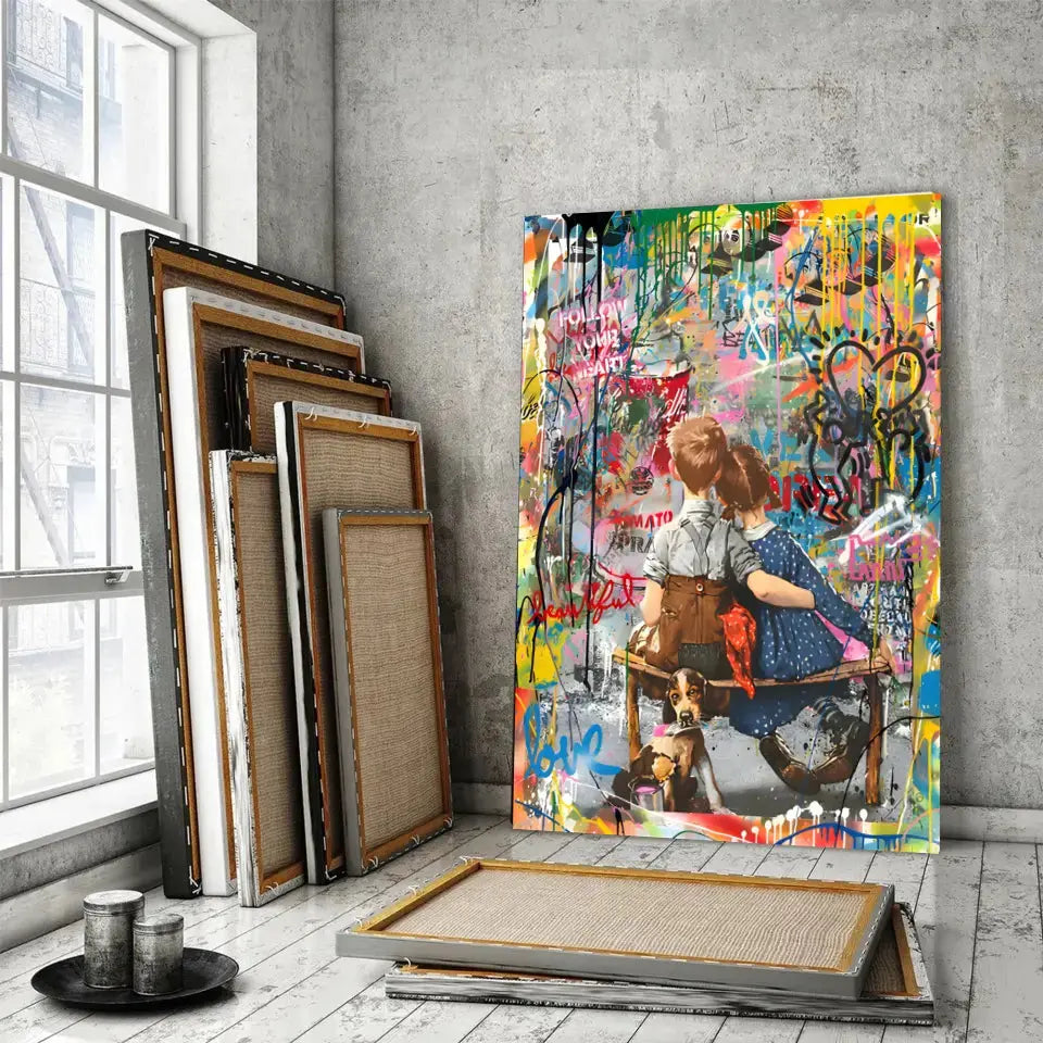 Tableau Street Art Complicité Urbaine sur toile, posé devant des cadres empilés près d'une fenêtre