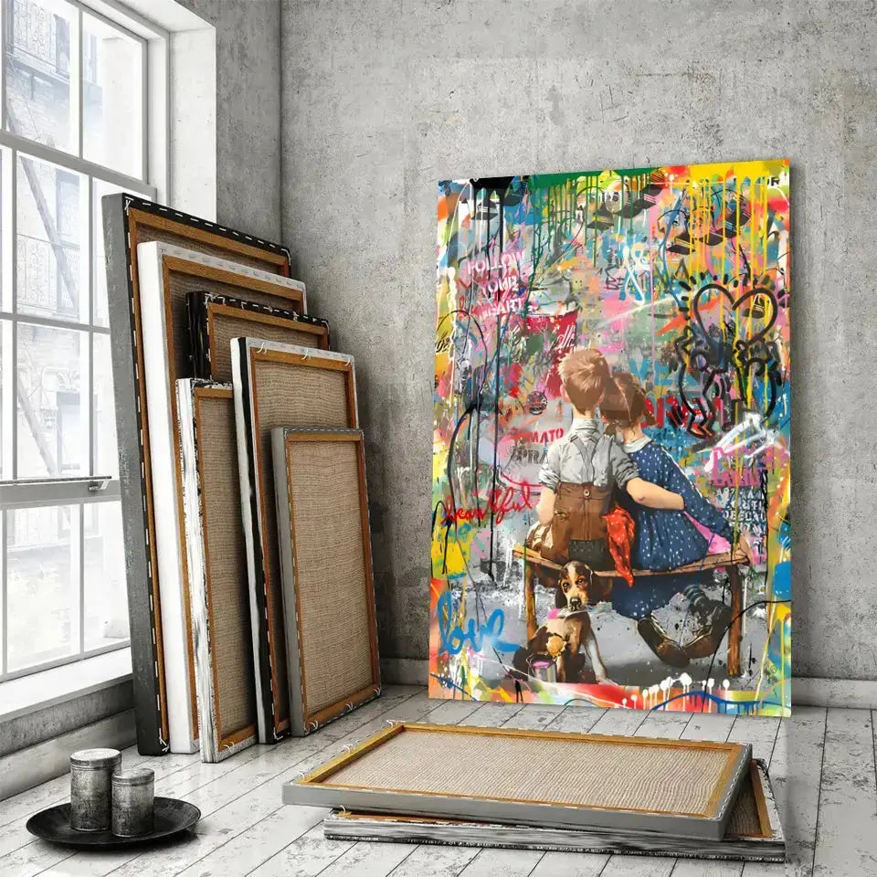Tableau Street Art Complicité Urbaine en verre acrylique, posé devant des cadres empilés