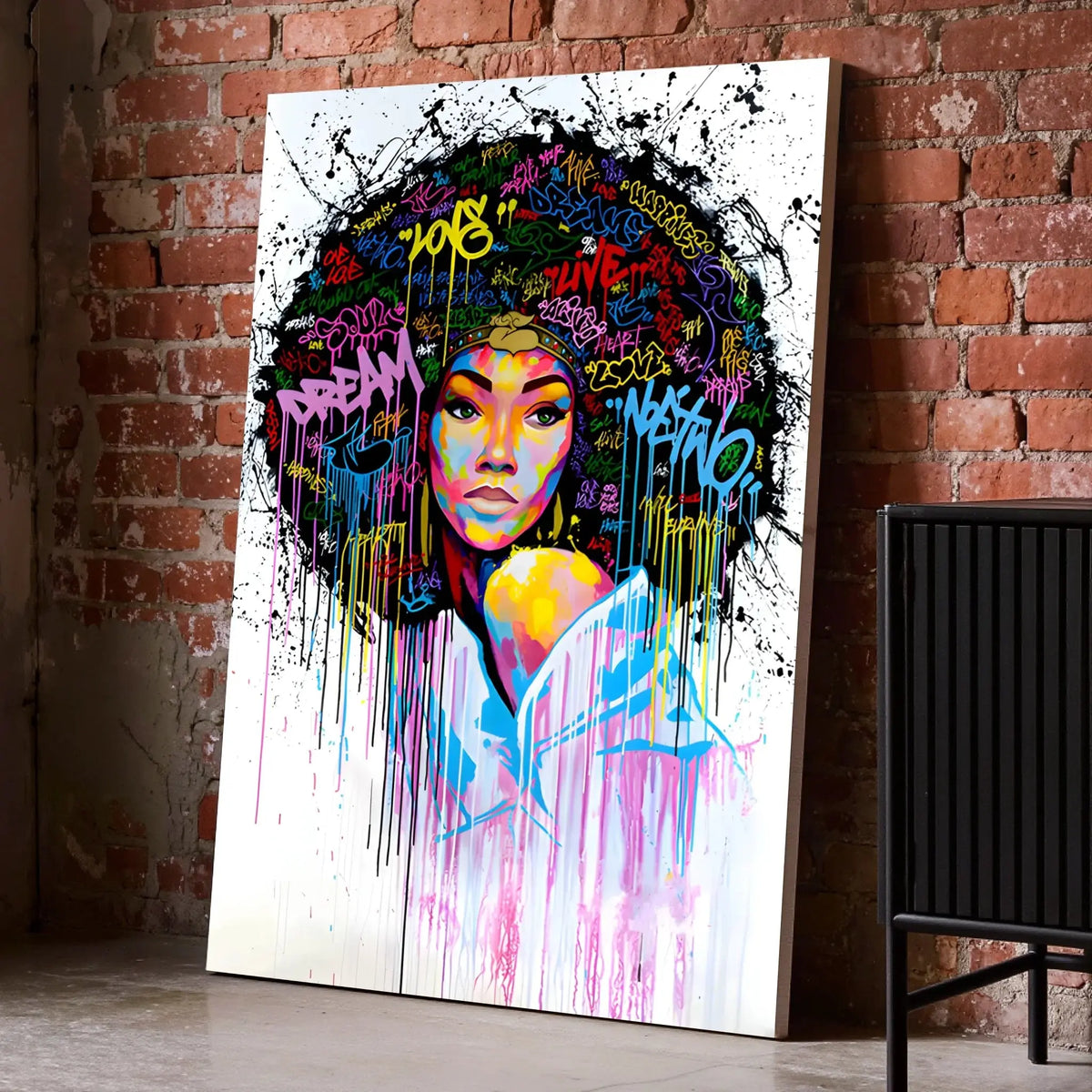 Tableau Street Art Éclat Afro sur toile, posé au sol contre un mur de briques rouges