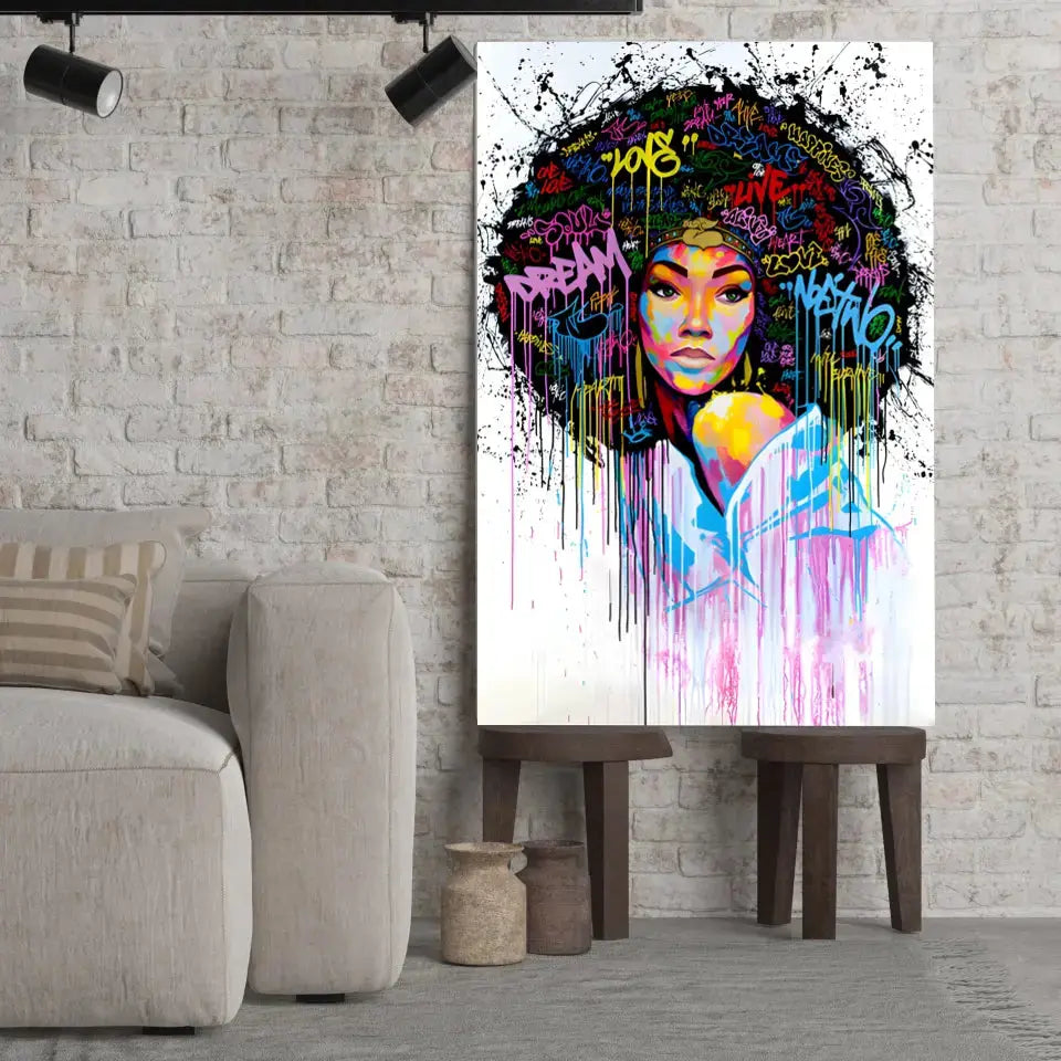 Tableau Street Art Éclat Afro sur toile, posé sur des tabourets devant un mur de briques