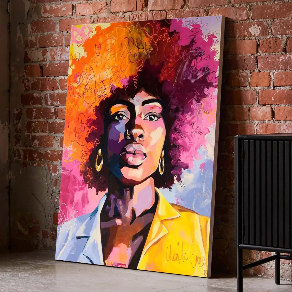 Tableau Street Art Femme Afro sur toile, posé au sol contre un mur de briques rouges