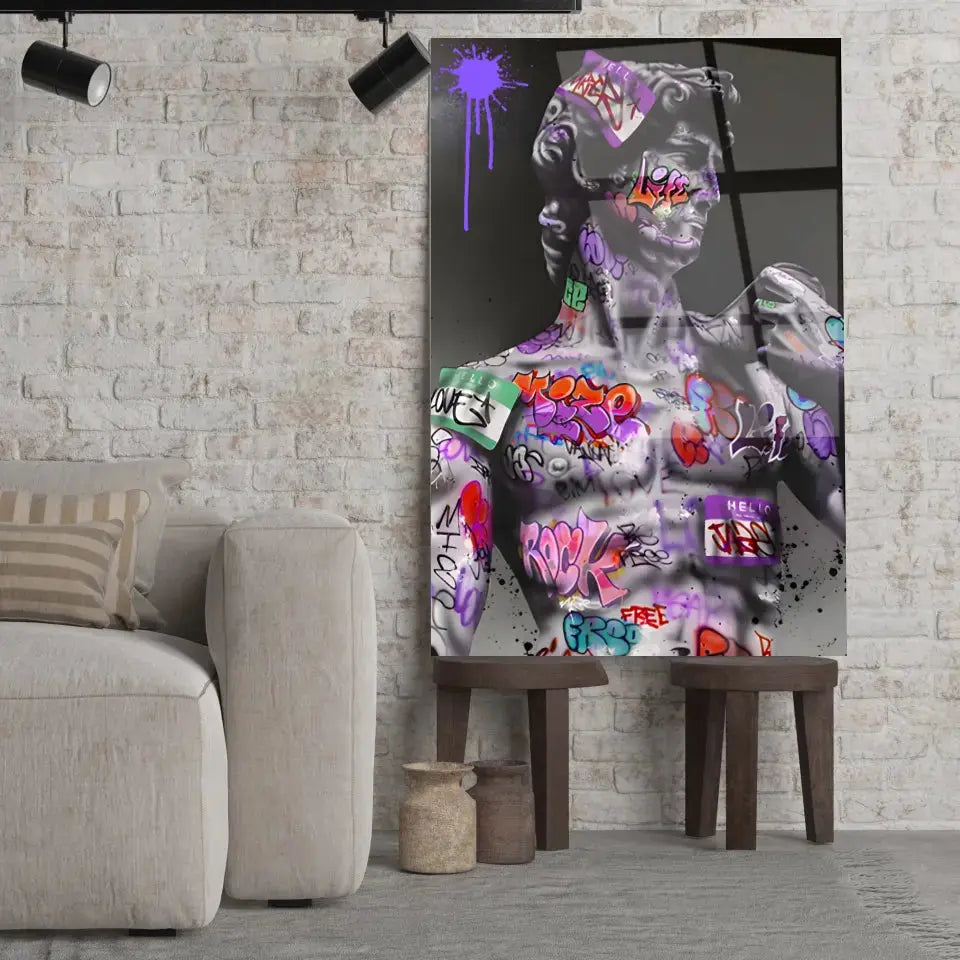 Tableau Street Art Héritage Urbain en verre acrylique, posé sur des tabourets devant un mur de briques