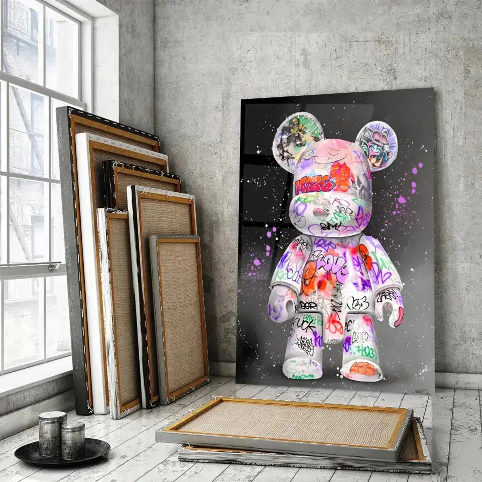 Tableau Street Art Kaws Bearbrick en verre acrylique, posé devant des cadres empilés