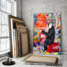Tableau Street Art Pause Urbaine sur toile, posé devant des cadres empilés près d'une fenêtre
