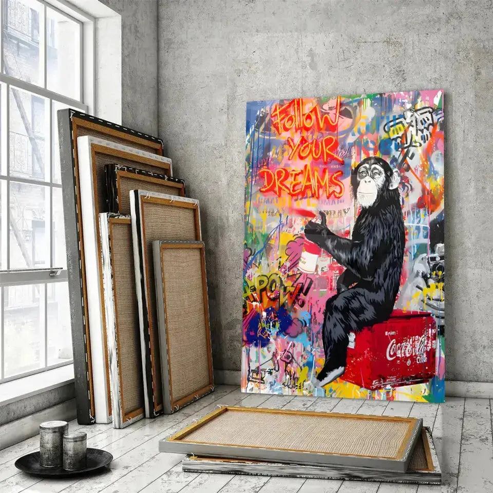 Tableau Street Art Pause Urbaine en verre acrylique, posé devant des cadres empilés