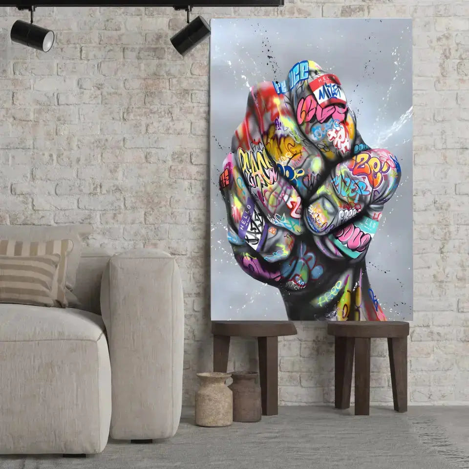 Tableau Street Art Poing de Révolte sur toile, posé sur des tabourets devant un mur de briques