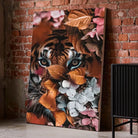 Tableau tigre feuillage sur toile, posé au sol contre un mur de briques rouges