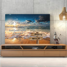 Toile prénoms personnalisée plage et coucher de soleil posée sur un meuble bas, décoration salon